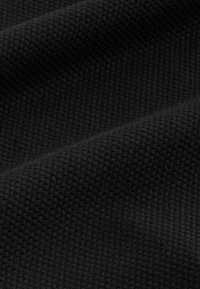 Tissu noir texturé avec un motif tissé, présentant une surface légèrement surélevée. Le matériau semble durable et flexible.