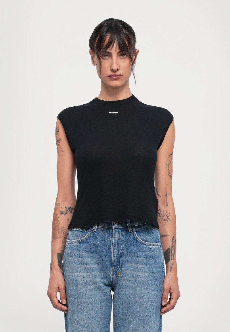 Black, sleeveless crop top made of ribbed fabric with a high neck. Features a small branded logo on the front. Paired with blue jeans.