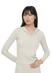 Prążkowana, jasnobeżowa bluza z kapturem na zamek błyskawiczny o minimalistycznym designie, z długimi rękawami i kapturem. Posiada krótki dół i fakturowaną tkaninę.