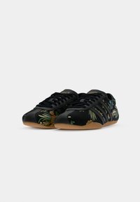 Svarta sneakers med blommig broderi i grönt och orange, med tre svarta ränder, låg profil och sula i gummirubber.