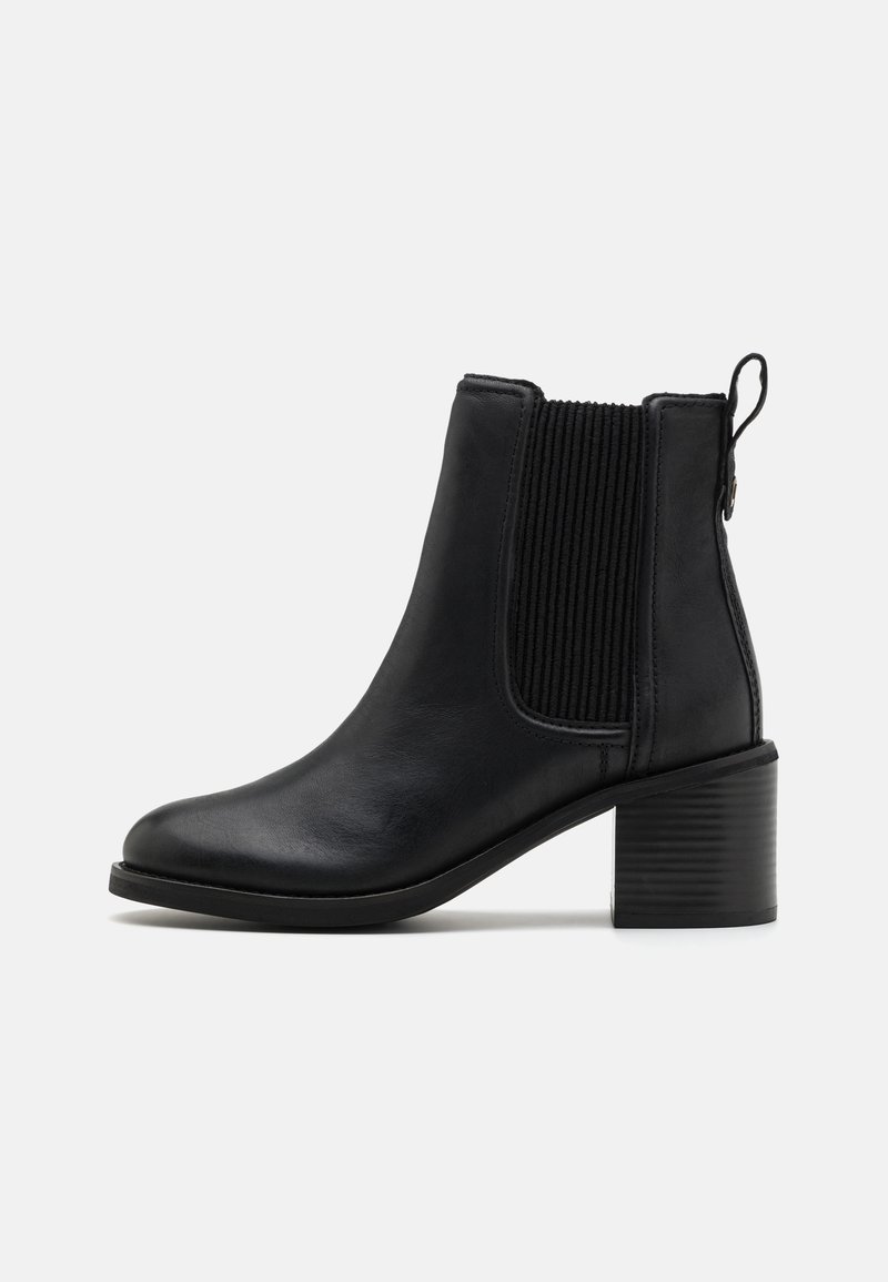 Botte de cheville en cuir noir avec des panneaux latéraux en élasthanne côtelé, design minimaliste, bout rond et un talon bloc texturé.