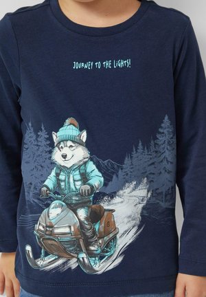 Marineblaues Langarm-T-Shirt mit einem Cartoon-Husky auf einem Schneemobil, mit einem hellblauen Design, einer strukturierten Berglandschaft im Hintergrund und dem Text „Reise zu den Lichtern!“