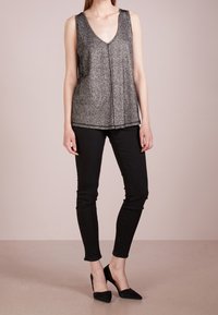 Top senza maniche nero con scollo a V profondo, realizzato in un materiale texturizzato e luminescente, con un taglio dritto e delicati dettagli sull'orlo.