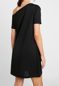 Černé šaty bez ramínek vyrobené z měkké tkaniny, s krátkými rukávy, volným střihem a rovnými lemy. Minimalistický design.