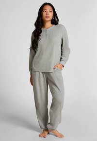 Grå mysset med långärmad tröja med henley-hals och matchande löst sittande byxor, tillverkade av mjukt texturerat tyg.