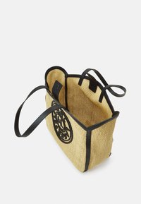 Sac fourre-tout en paille tissée avec des finitions en cuir noir et des anses pour l'épaule ; arbore un emblème rond sur le devant. Design à ouverture sur le dessus, intérieur spacieux.