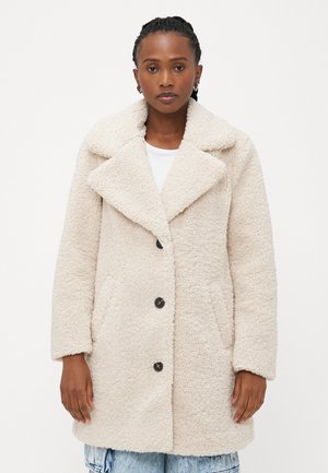 Manteau en fausse laine de mouton couleur crème avec un large col, des boutons sur le devant et des poches latérales ; coupe décontractée avec des épaules tombantes et une texture moelleuse.