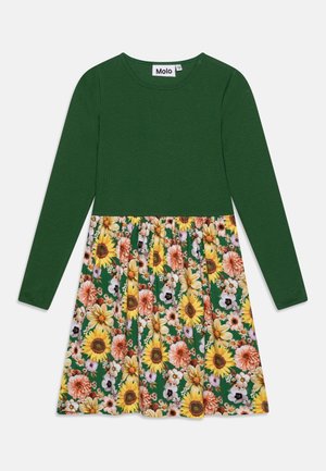 Vestido verde de manga larga con cuello redondo y falda con un llamativo estampado floral que incluye girasoles y otras flores.