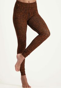 Leggings i ett texturerat mönster av svart och orange, med hög midja och åtsittande design, idealiska för komfort och rörelse.