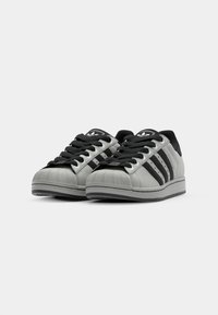 Gray leather sneakers with black accents. Features classic three stripes, a textured rubber toe cap, and flat black laces.