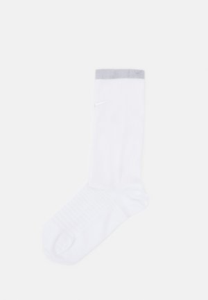Weiße Sportsocke mit grauem Rippbund, ausgestattet mit einem dezenten Logo und einer strukturierten Fußbett für besseren Halt, entworfen für Komfort und Leistung.