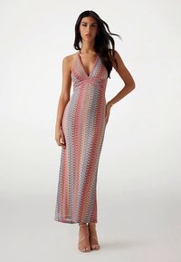 Maxi-jurk met halternek en een meerkleurig golfpatroon. Gemaakt van licht, doorschijnend stof, met een aansluitend silhouet en zijopeningen.