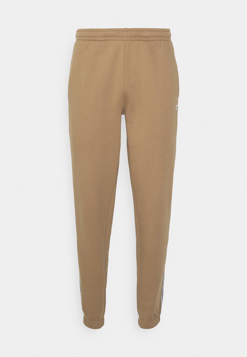 Pantalons de survêtement marron avec une taille à cordon coulissant, des jambes fuselées et des poignets élastiques. Détails du logo et panneaux latéraux contrastés. Texture douce.