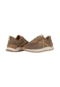 Zapatos deportivos de ante marrón con suela de goma beige, que cuentan con acentos cosidos y un diseño minimalista. Cuentas con cordones y un logo en la lengüeta.