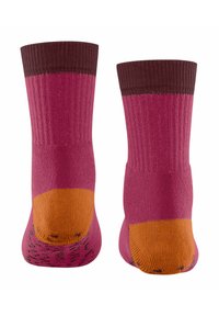 Para różowych skarpetek sięgających do połowy łydki z ciemnobrązowymi mankietami oraz wzmocnionymi pomarańczowymi piętami i palcami, pokazanych z tyłu.