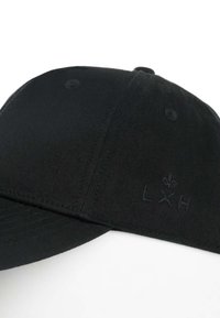 Cappello in cotone nero con visiera curva, caratterizzato dal logo ricamato "LXH" e un accento a forma di giglio. Tessuto testurizzato con dettagli cuciti.