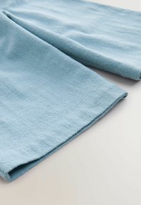 Világoskék szövet, texturált halszálka mintával, hajtogatott szélekkel és puha felülettel. Különböző textil alkalmazásokhoz alkalmas.