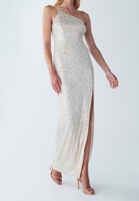 Abito da sera in paillettes color beige chiaro, caratterizzato da un design monospalla, alta apertura laterale e una silhouette aderente con una fodera interna liscia.