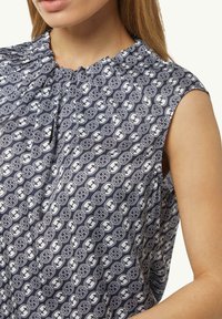 Marineblouse met een ronde halslijn en korte mouwen, voorzien van een herhalend wit patroon. Zachte stof met een lichte glans en geplooide details.