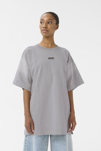 T-shirt grigia oversize realizzata in tessuto morbido, con maniche corte e colletto girocollo. Piccolo logo nero centrato sul davanti.