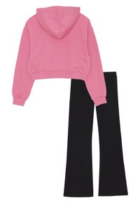 Felpa corta rosa con maniche lunghe abbinata a pantaloni neri a vita alta e a zampa, distesi su uno sfondo bianco.