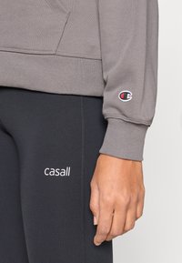 Γκρι φούτερ με ριμπ μανσέτες και λογότυπο στο μανίκι, συνδυασμένο  με μαύρο κολάν που διαθέτει λευκό κείμενο. Μαλακό ύφασμα, εφαρμοστή σχεδίαση.