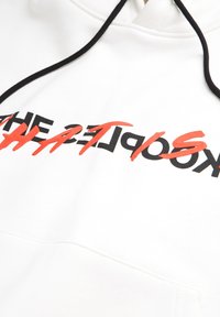 Sweat à capuche blanc avec un imprimé graphique noir et rouge. Il comprend une capuche avec cordon de serrage et un tissu texturé avec des coutures visibles.