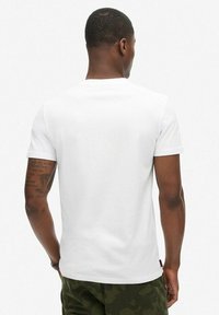 T-shirt bianco in cotone con maniche corte e scollatura a girocollo, con etichetta sull'orlo. Tessuto morbido, vestibilità casual.