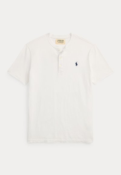 Άσπρο πόλο μπλουζάκι με γιακά χένλεϊ, διαθέτοντας τρία κουμπιά και ένα μικρό ναυτικό μπλε λογότυπο στο αριστερό στήθος. Υλικό από βαμβάκι με κοντά μανίκια.