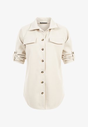 Crèmekleurig shirt met lange mouwen, opgerolde mouwen, knoopsluiting aan de voorkant en twee borstzakken met klep.