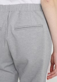 Grå sweatpants med en strukturerad yta, utrustade med två bakfickor och resår i midjan. Sidostrimlor i vitt.