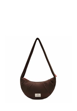 Sac d'épaule marron en forme de croissant avec une longue sangle et une petite étiquette blanche à l'avant, sur un fond blanc.