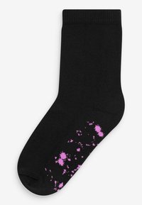 Chaussette noire avec une texture côtelée, ornée de motifs éclaboussés roses près de la zone des orteils. Le design est simple et moderne.