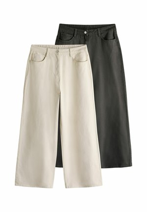 Pantalons évasés en denim crème et noir, avec poches avant et fermeture à bouton. Texture lisse avec une finition soignée.