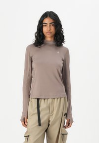Brauner Langarmshirt mit einer taillierten Passform und Mock-Neck. Mit einem kleinen Logodetail auf der Brust und einem glatten, dehnbaren Stoff.