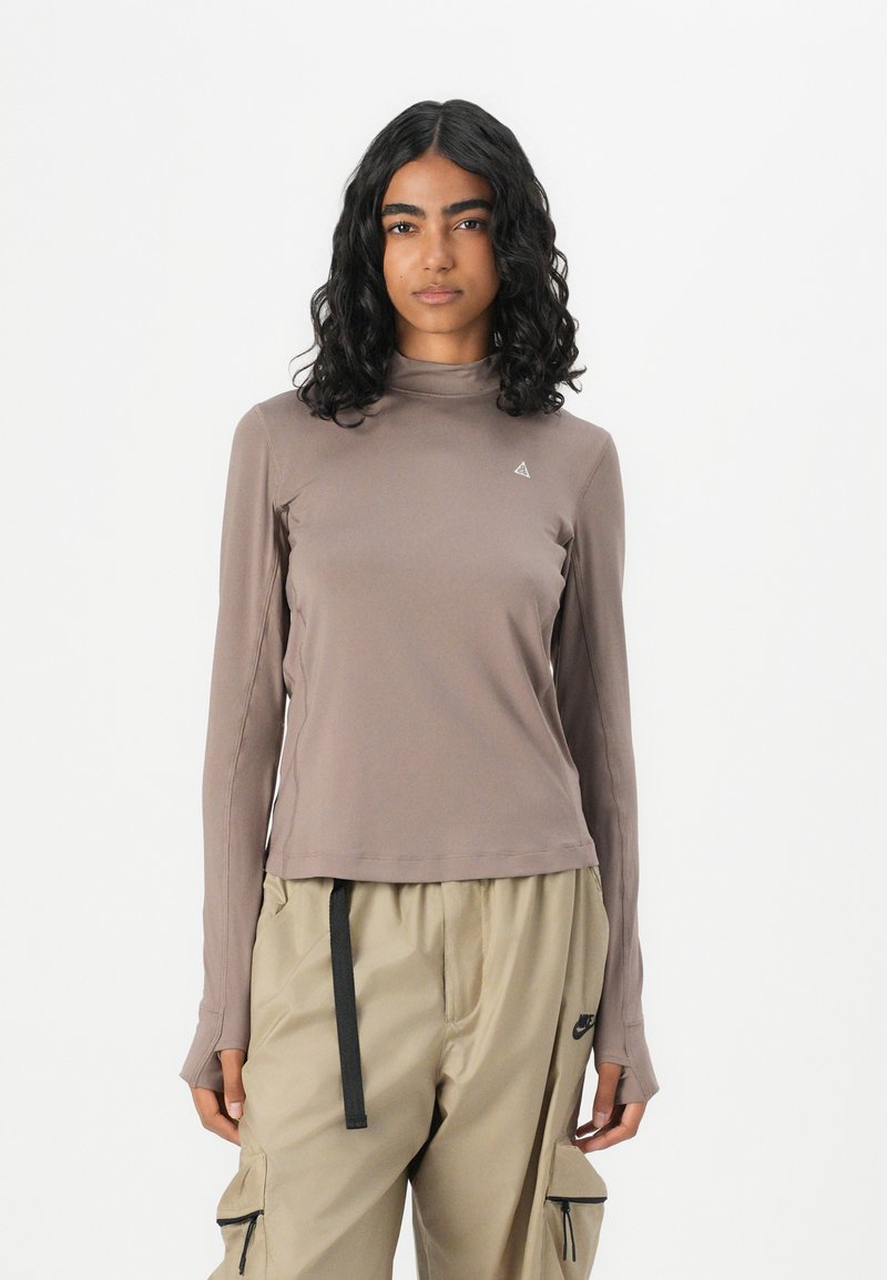 Brauner Langarmshirt mit einer taillierten Passform und Mock-Neck. Mit einem kleinen Logodetail auf der Brust und einem glatten, dehnbaren Stoff.