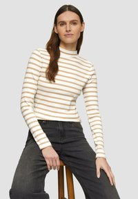 Rippstrick-Oberteil mit langen Ärmeln in Creme mit taupefarbigen Streifen. Verfügt über einen hohen Kragen und eine figurbetonte Passform. Kombiniert mit dunklen, hochgeschnittenen Jeans.