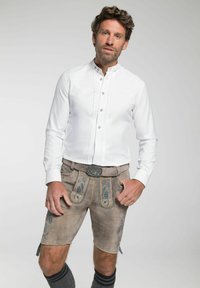 Wit button-up shirt met pintucks, gecombineerd met tan lederhosen met blauwe bloemenborduursel en een grijze riem met een decoratieve gesp.