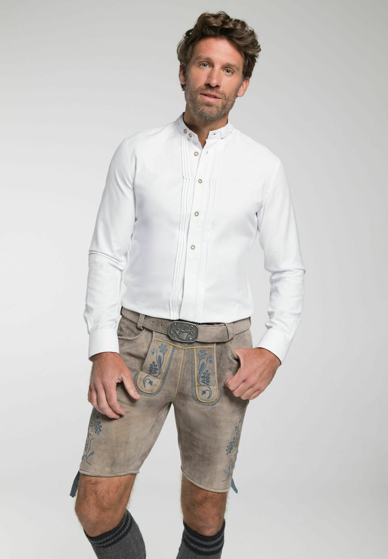 Wit button-up shirt met pintucks, gecombineerd met tan lederhosen met blauwe bloemenborduursel en een grijze riem met een decoratieve gesp.
