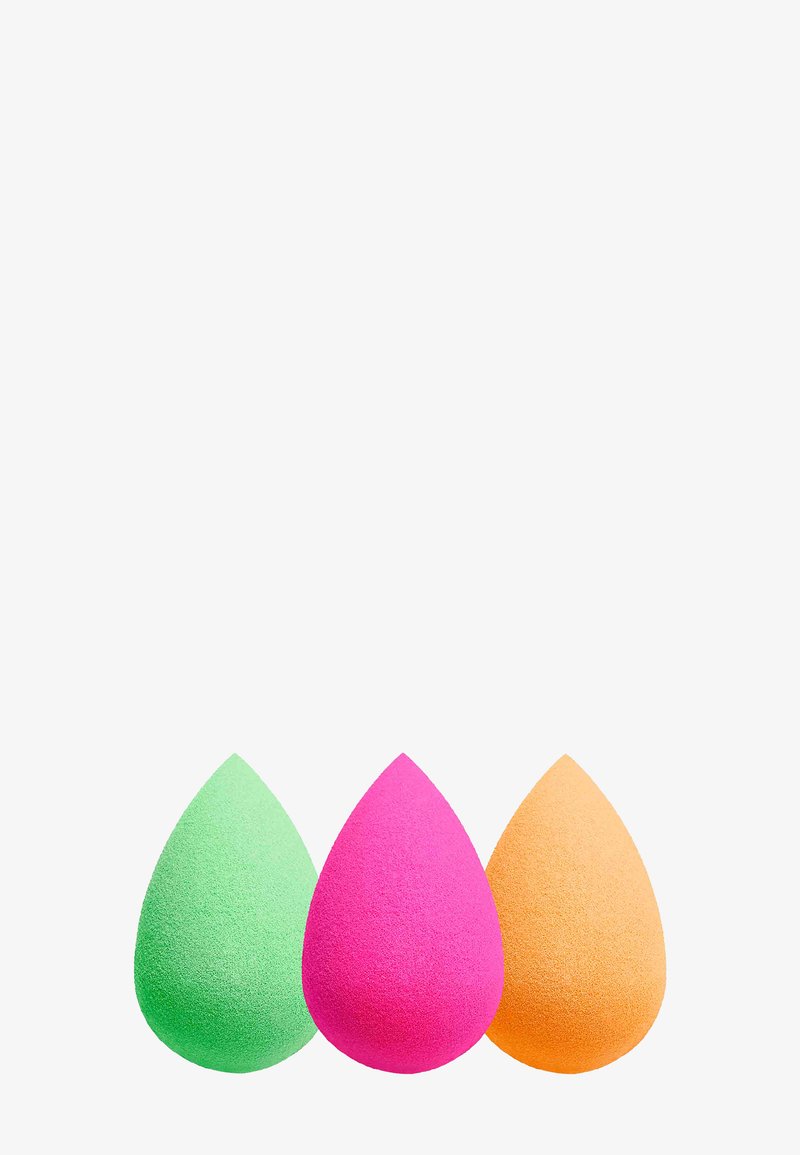 Tre spugnette per il trucco a forma di lacrima, verdi, rosa e arancioni, su uno sfondo bianco.
