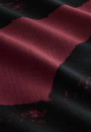 Textile featuring a woven fabric with a smooth texture, dark black base, and bold burgundy abstract patterns creating contrasting shapes.