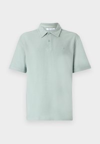 Polo vert clair à manches courtes avec un col et deux boutons, en tissu doux texturé, présenté sur un fond blanc uni.