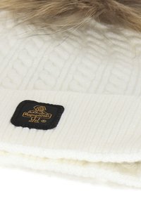 Berretto bianco lavorato a maglia con texture a coste, dotato di un pon-pon staccabile in pelliccia sintetica marrone e di un'etichetta nera con accento dorato del logo.