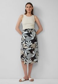 Zwarte wikkelrok met lichtblauwe en beige bladvormen, gecombineerd met een crèmekleurig tanktop en witte instap-sandalen. Gladde textuur, casual ontwerp.