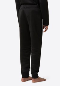 Čierne termo nohavice s textúrovaným povrchom, vybavené elastickým pásom a zúženými nohavicami, navrhnuté pre teplo a pohodlie.