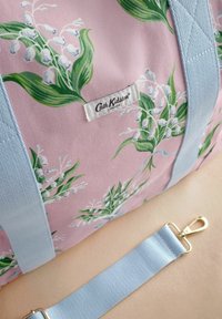 Różowa torba podróżna z tkaniny z zielonym wzorem kwiatowym, jasnoniebieskimi paskami i złotym zapięciem. Posiada metkę z logo Cath Kidston.