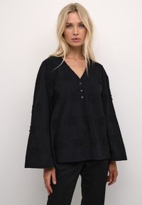 Blusa nera ricamata con scollatura a V, chiusura frontale a bottoni e maniche a campana con motivi floreali testurizzati.