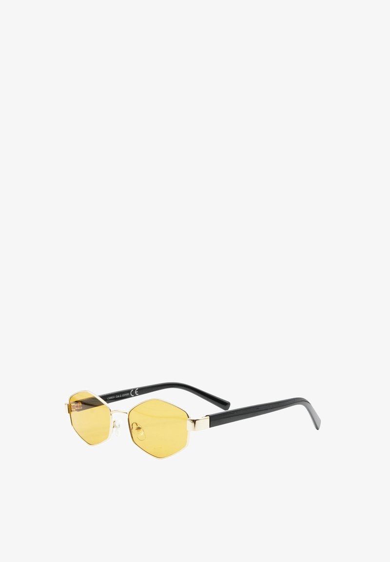 Occhiali da sole esagonali tinti di giallo con sottili montature in metallo dorato e aste in plastica nera su sfondo bianco.