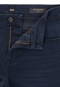 Mörkblå slim fit jeans med delvis upplåst dragkedja, knappstängning och Hugo Boss-etiketter inuti midjebandet.