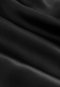 Glat sort stof med en satinfinish, der viser en blød tekstur og subtil glans. Materialet er draperet og skaber bløde folder.